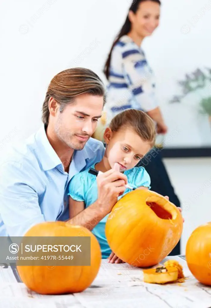 A young father helping his daughter to make a jack-o-lantern for Halloween