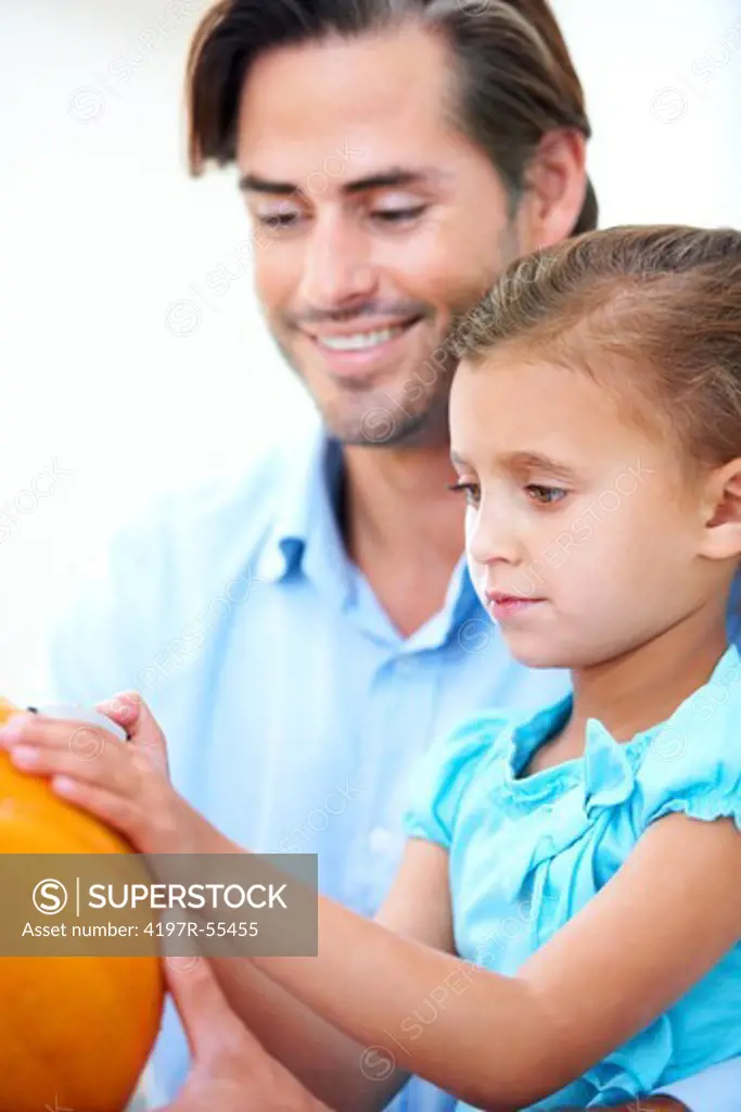 A father helping his little girl to make a jack-o-lantern for Halloween