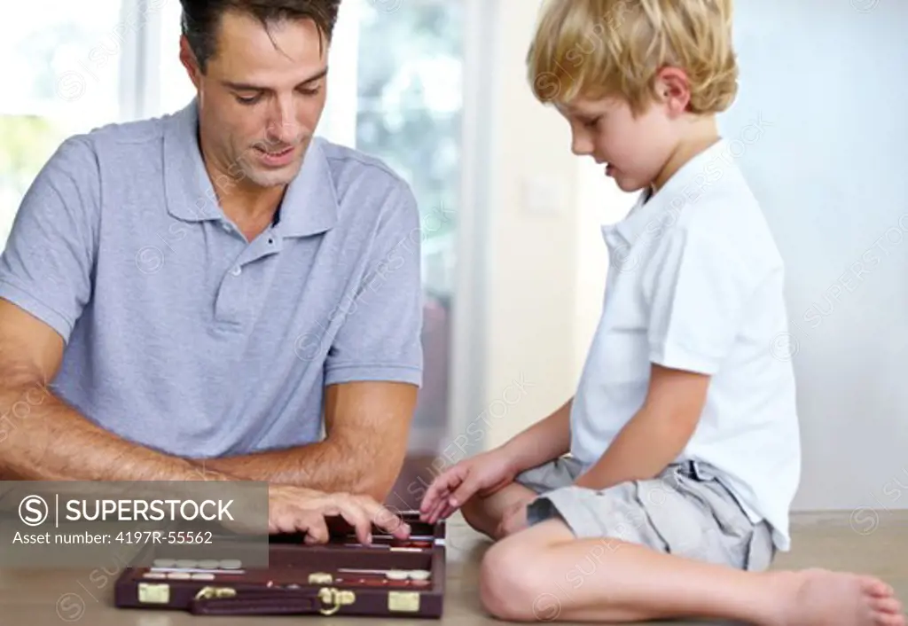 A father teaches his young son a lesson in the game of backgammon