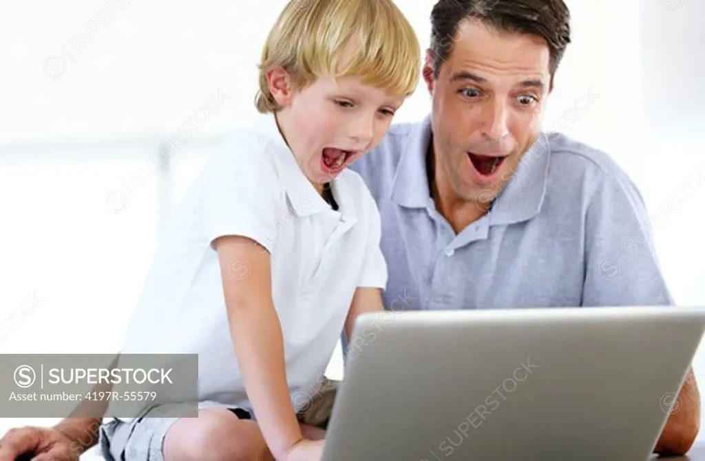 A father and son react with shock to something they have discovered while surfing the internet
