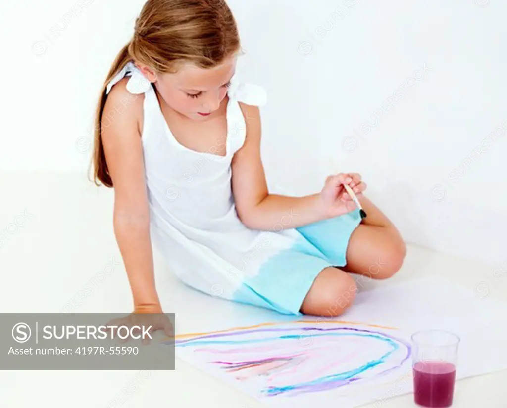 A little girl paints a rainbow while sitting on the floor