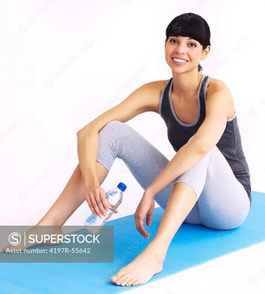 Portrait of a prety woman sitting on her yoga mat with a bottle of water