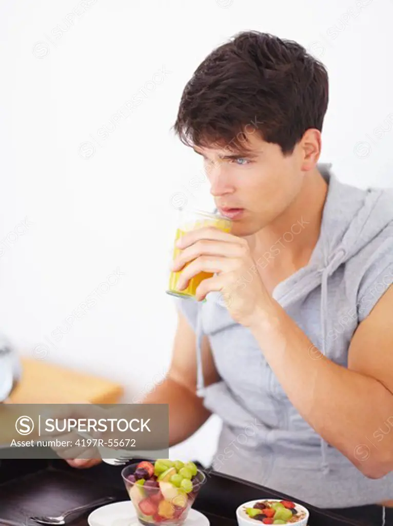 Handsome young guy enjoying a healthy fruit salad and juice