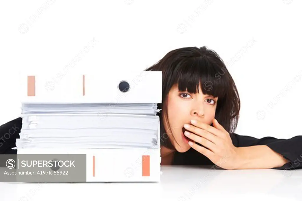 Exhausted young businesswoman sitting alongside a pile of files