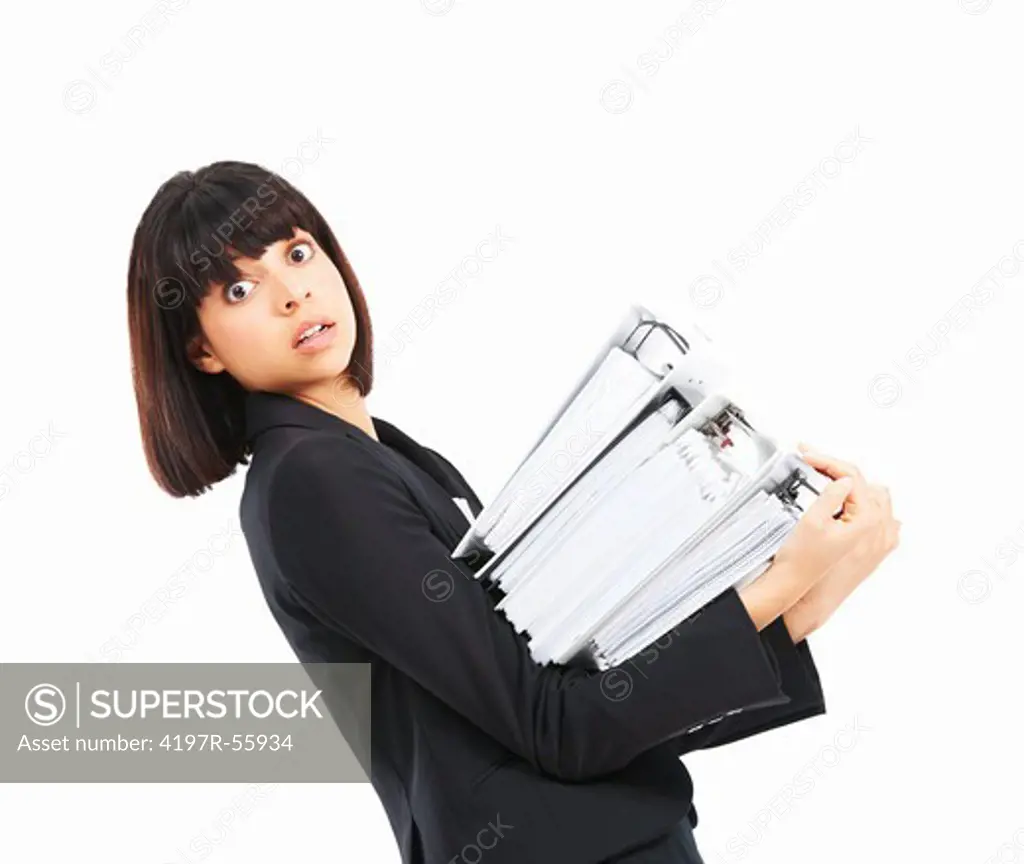 Stressed young businesswoman holding an armful of files while isolated on white
