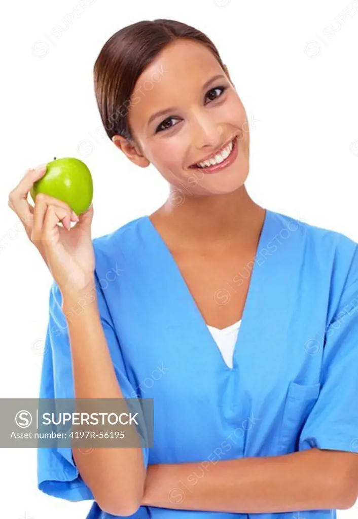 Pretty young nurse holding up an apple with a smile - isolated on white
