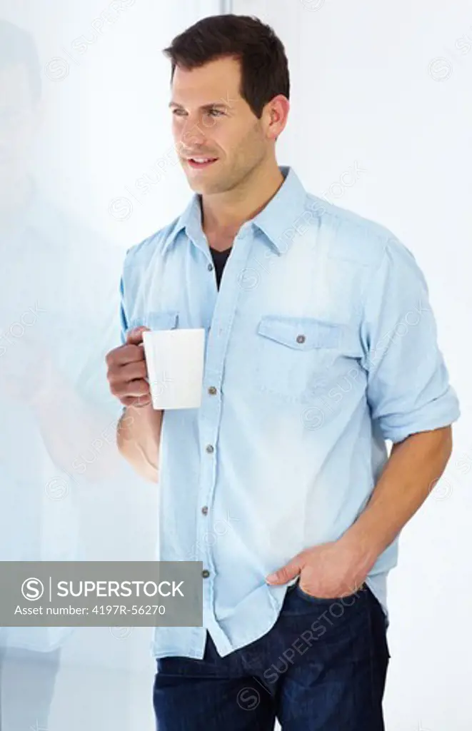 Young man enjoys a warm drink as he contemplates the day that lies ahead