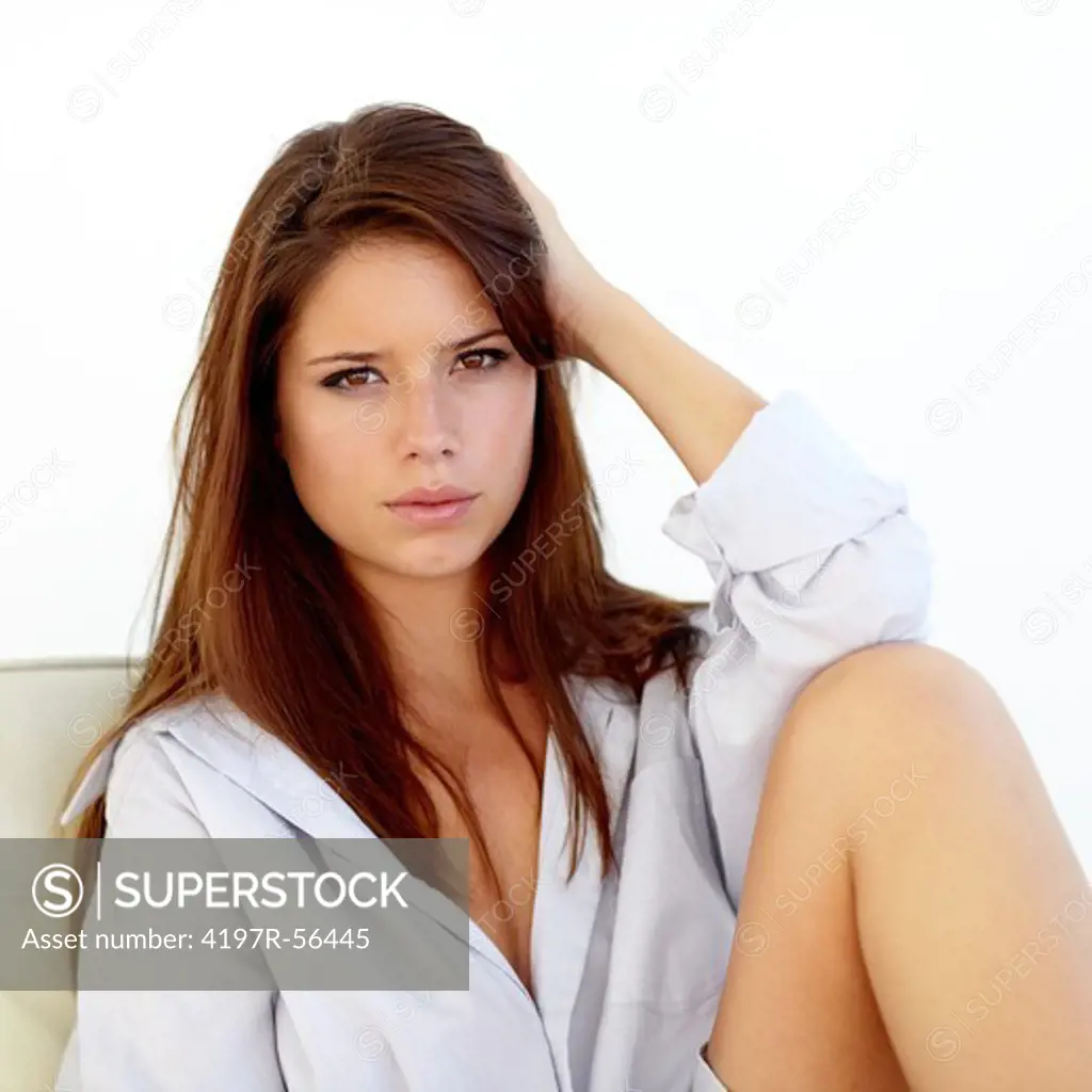 Sensual young woman in a shirt sitting isolated on white