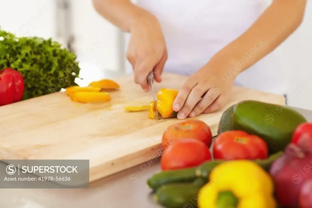 Cropped view of a young woman's hands as she chops vegetables