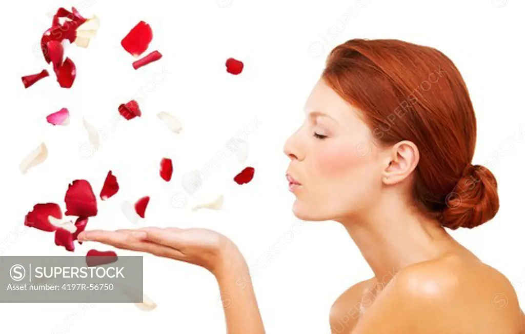 Profile of an attractive young woman blowing rose petals out of her hand