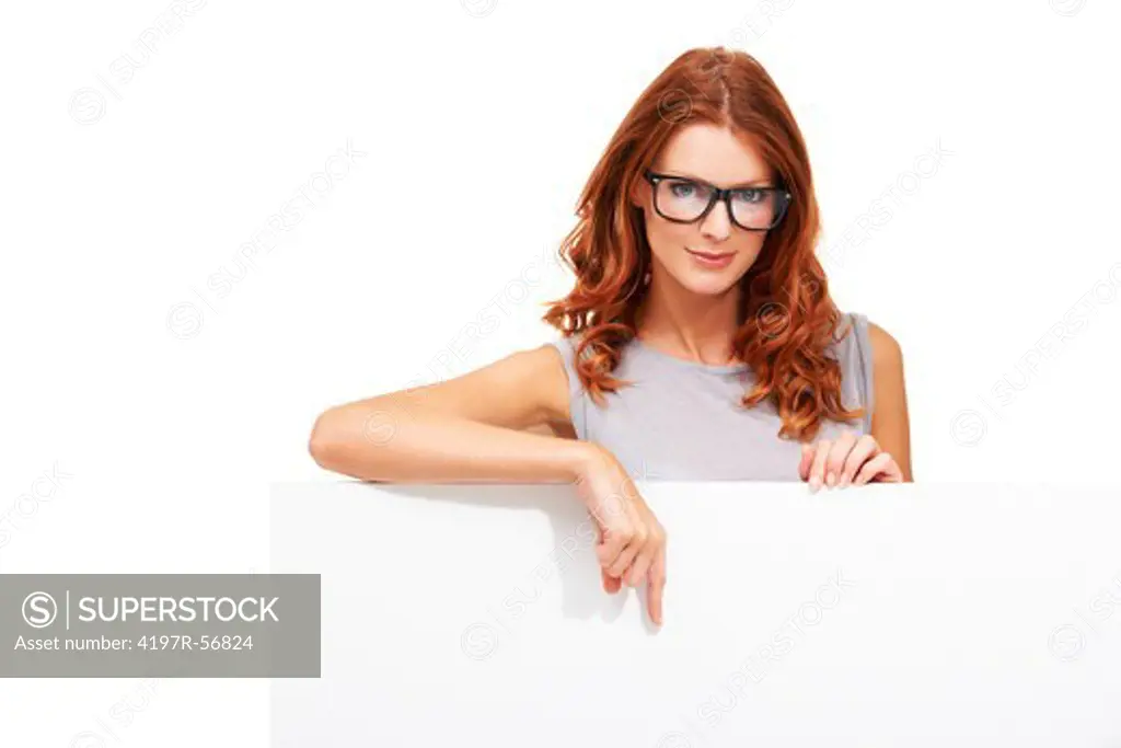 An attractive young woman wearing glasses and standing behind and pointing down to copyspace