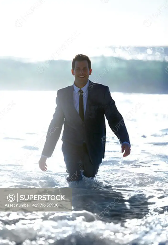 A young executive walking toward the camera through water and waves