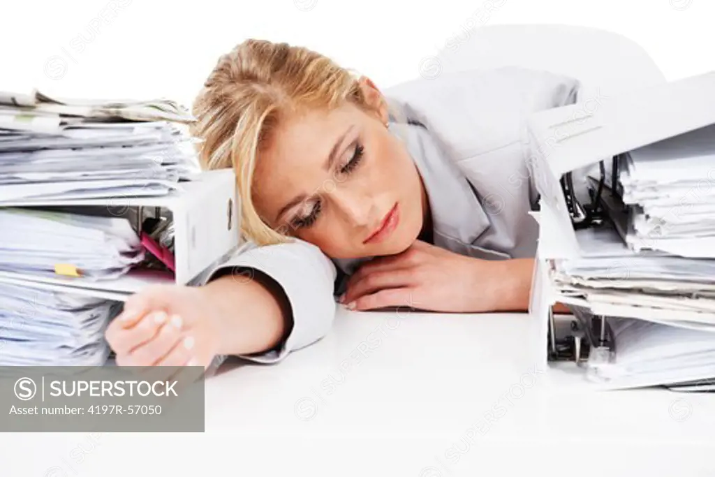 An exhausted businesswoman passed out between two piles of files at her desk