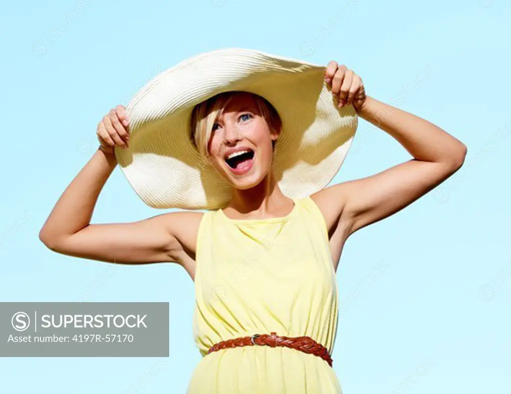 Portrait of a pretty young woman wearing sunhat with the blue sky behind her