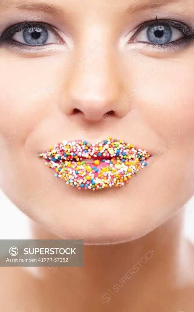 Portrait of a  beautiful young woman with multicoloured sweets on her lips