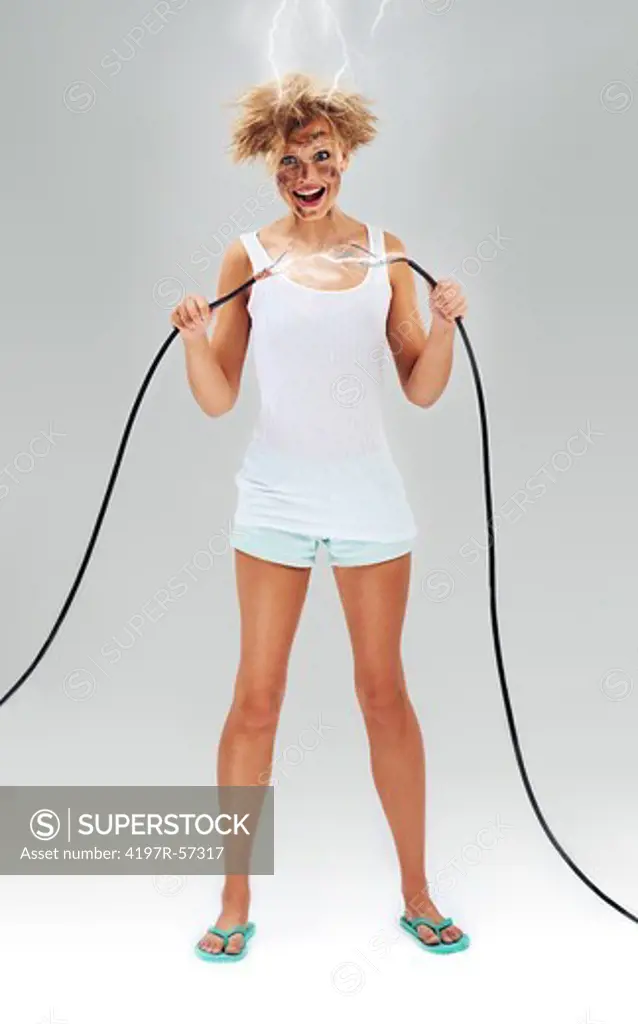 Untidy looking young woman holding power cables after receiving an electric shock