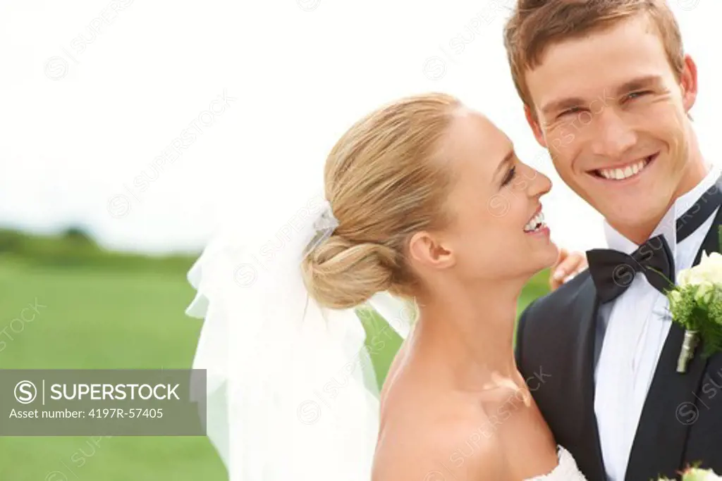 A new bride looks at her new husband lovingly while he smiles at the camera