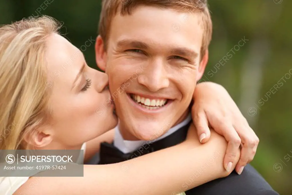 The new groom reacts happily to the tender kiss of his wife