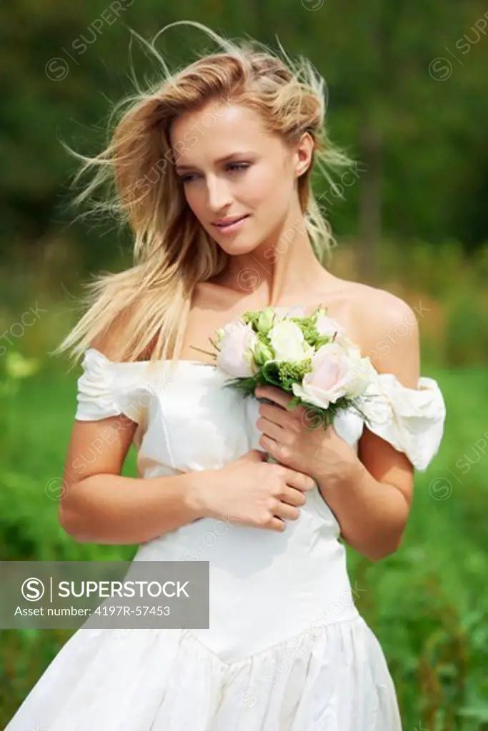 A 3/4 portrait of a happy new bride holding her boquet on the happiest day of her life