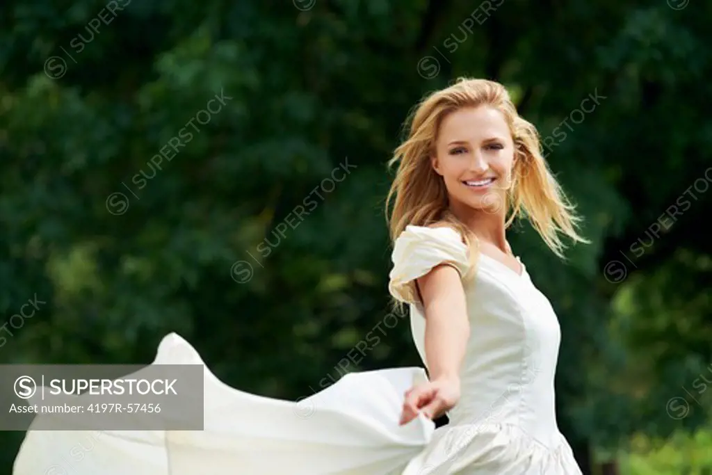 A beautiful young bride frolics in a field on her wedding day