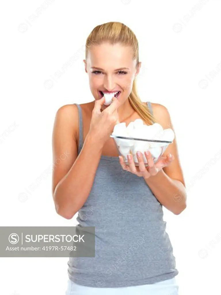 Happy young woman holding a bowl of marshmellows while eating one