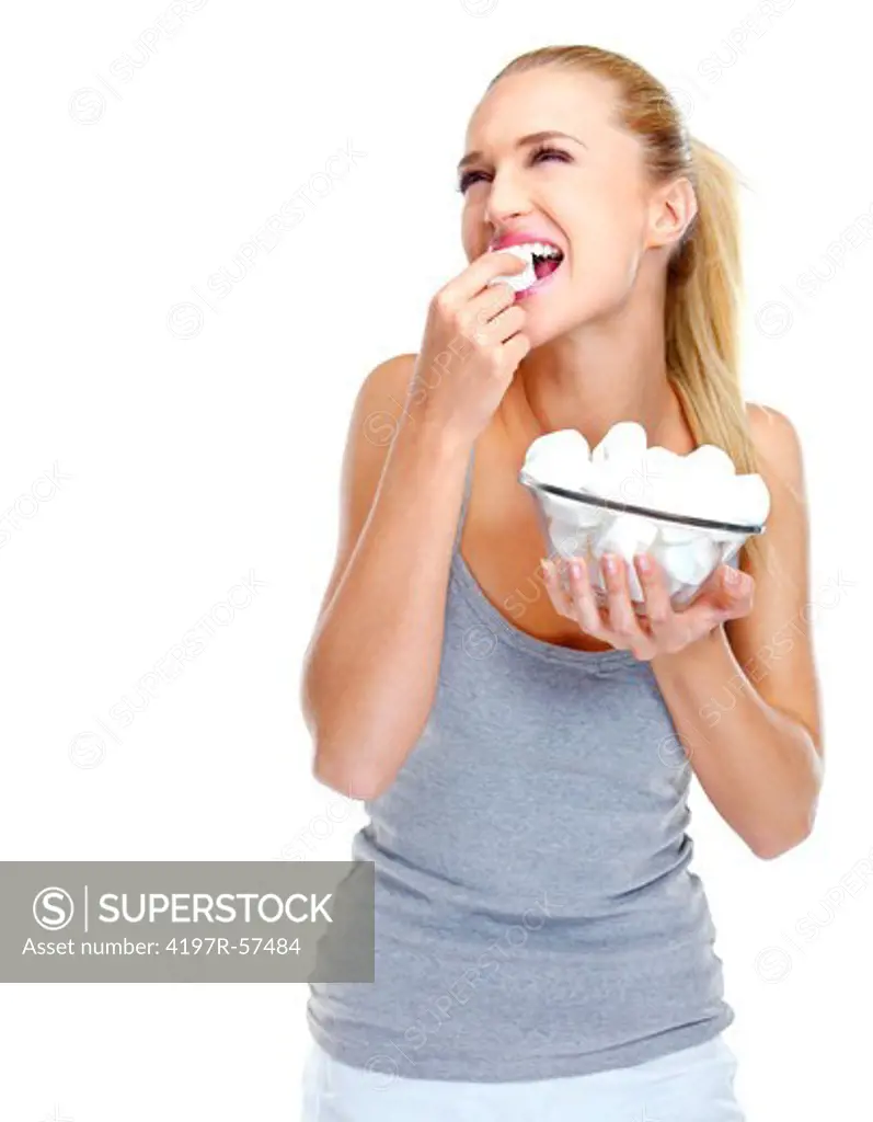 Smiling young woman holding a bowl of marshmellows while eating one