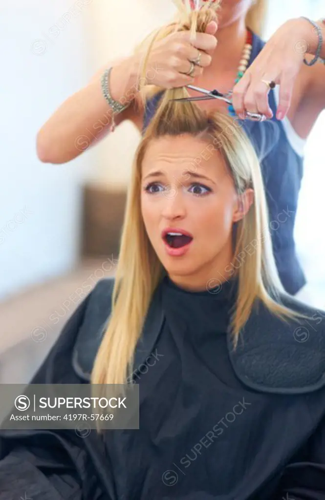 Shocked and dismayed young woman having a bad haircut at the salon