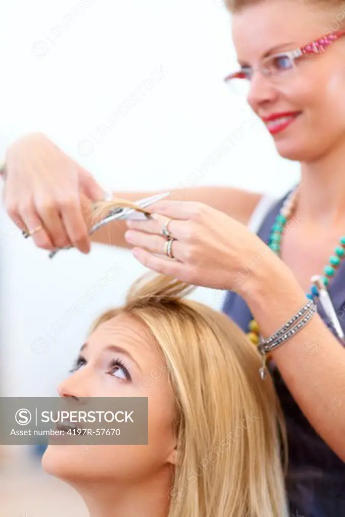 Worried young woman looking up as her hairstylist prepares to cut her hair