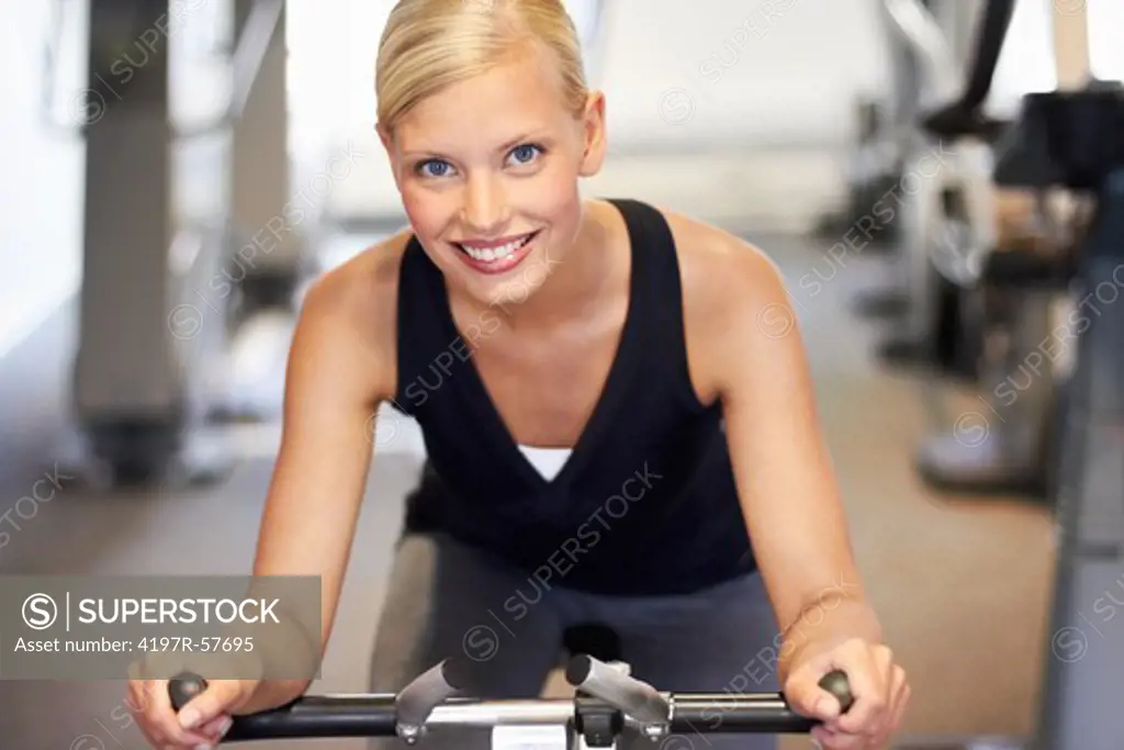 Portrait of an attractive young woman using an exercise bike in the gym