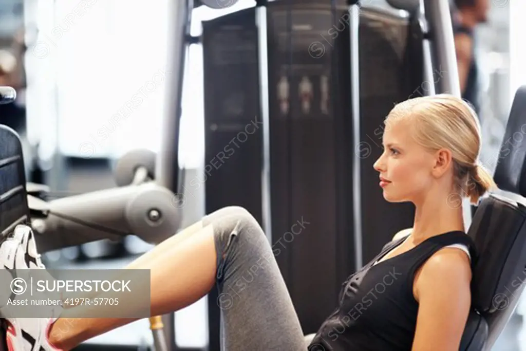 Profile of an attractive young woman on the leg machine in the gym
