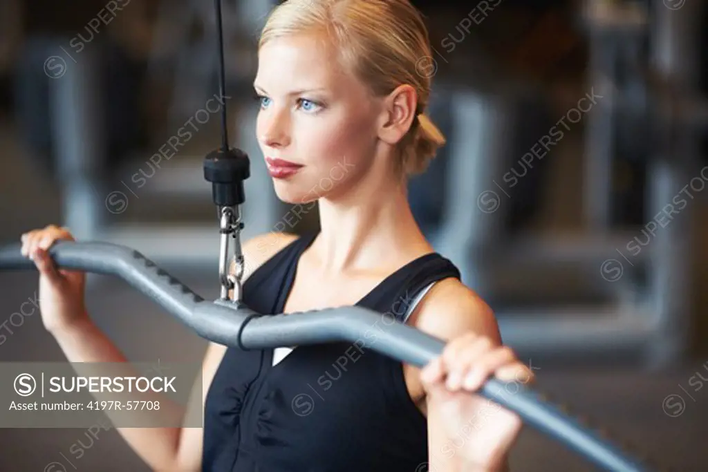 An attractive young woman working her shoulders in the gym
