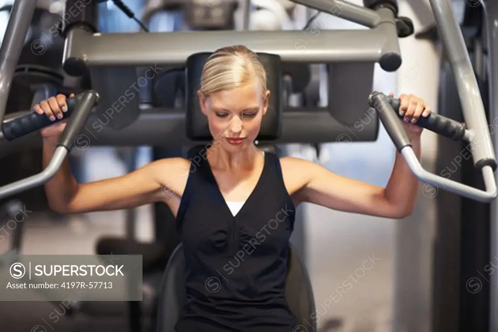 A beautiful young woman working her shoulders in the gym