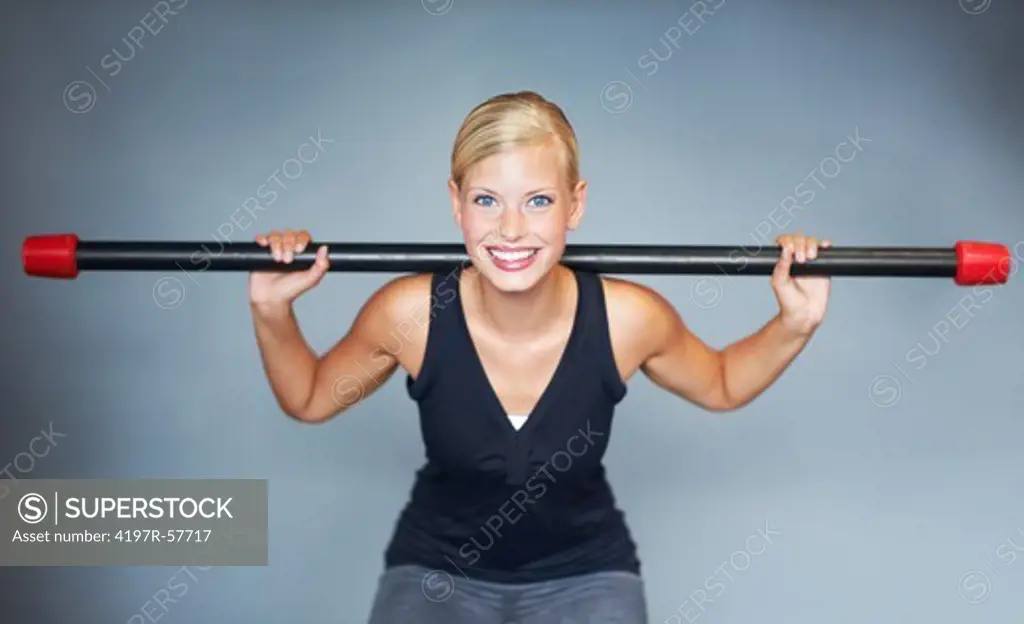 Portrait of an attractive young woman lifting a weighted bar in the gym