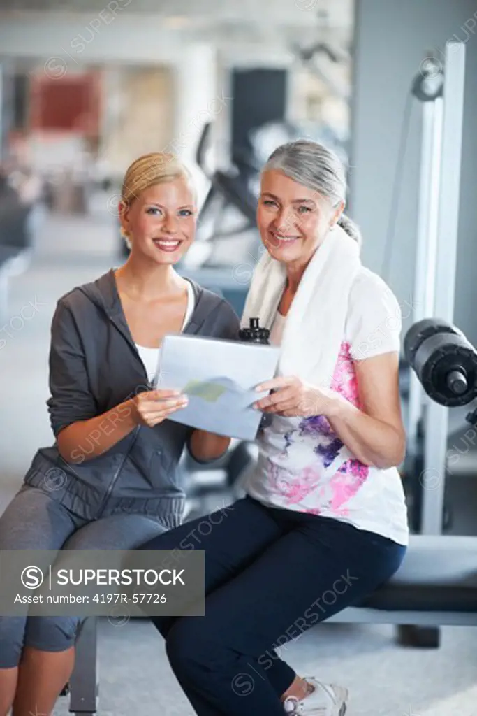 Portrait of a young female gym instructor helping an older woman