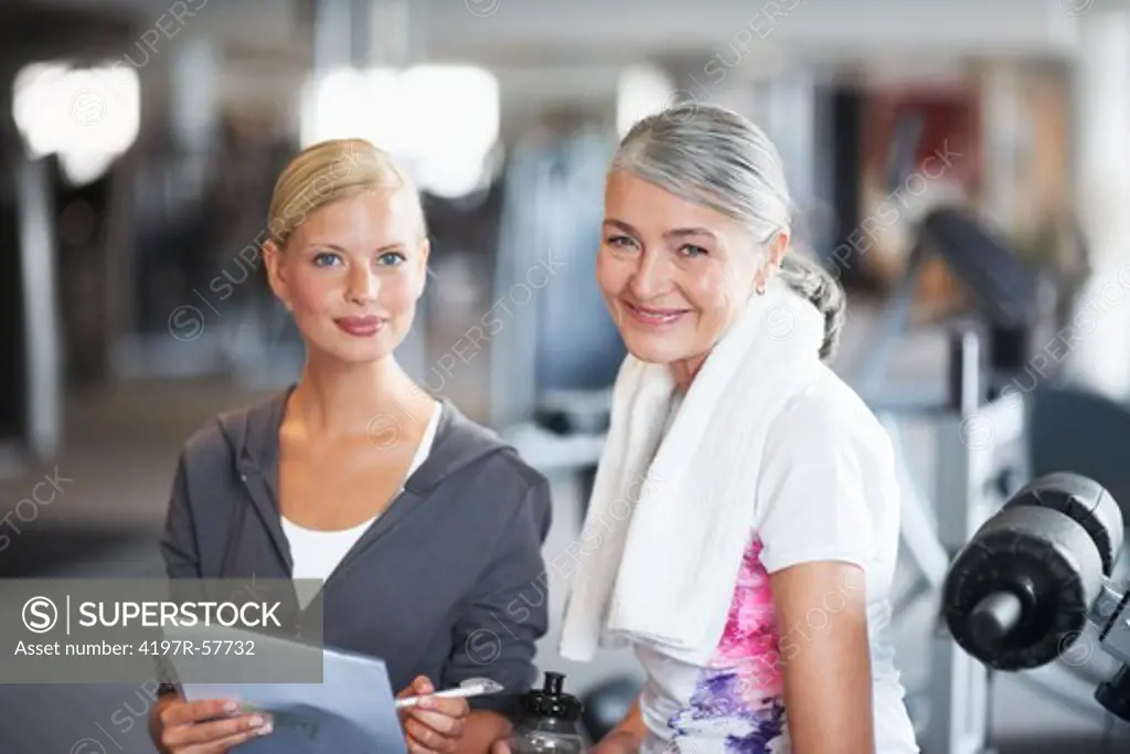 Portrait of a stunning female gym instructor helping an older woman