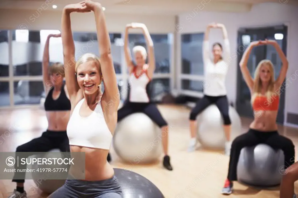 Portrait of a stunning young woman stretching with her aerobics class using exercise balls