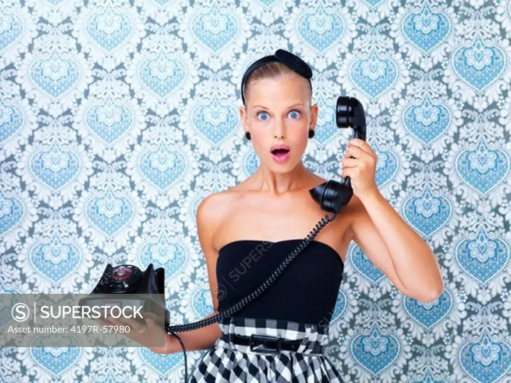 Lovely young woman on a retro telephone and receiving shocking news