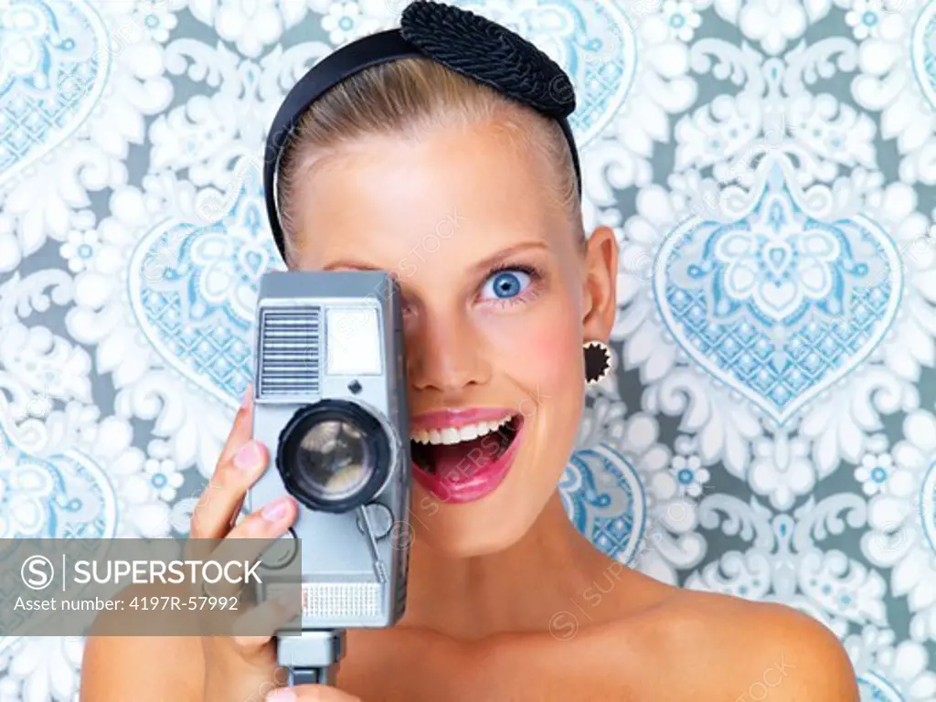 Suprised young woman using a retro video camera to film you