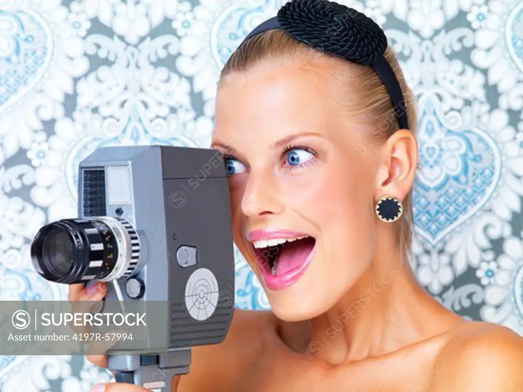 Excited young woman using a retro video camera to film something