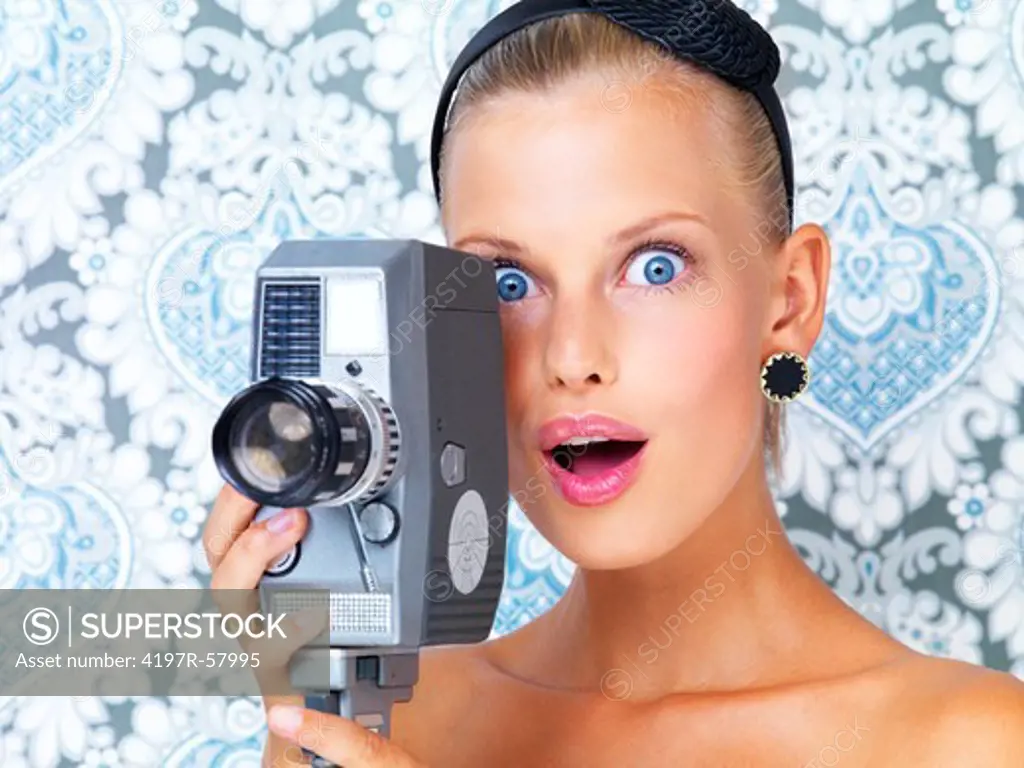Surprised young woman using a retro video camera to film something