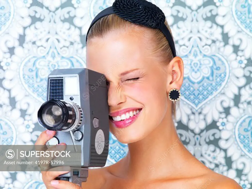 Cute young woman using a retro video camera to film something