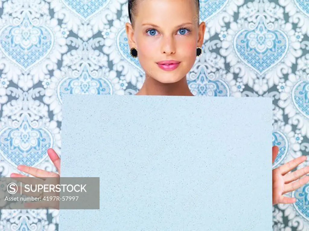 Pretty young woman holding up a board of copyspace while standing in front of a retro background