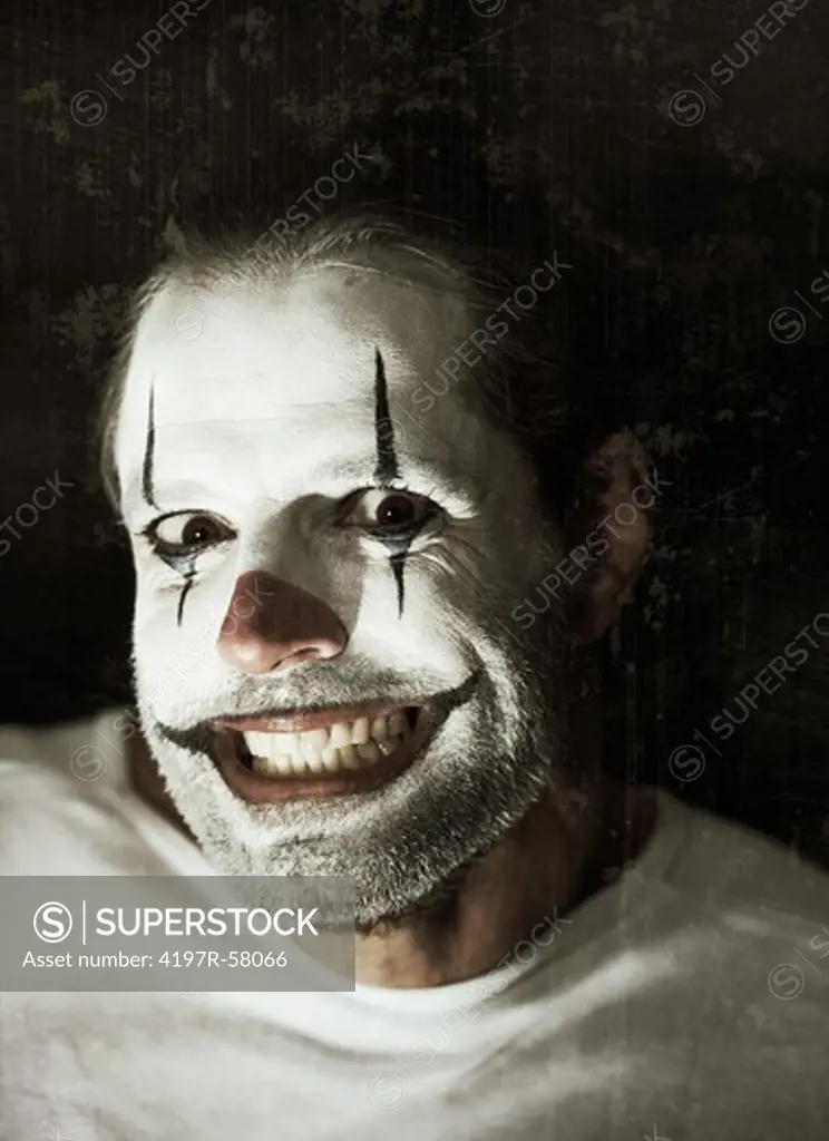Portrait of an evil clown with face paint on a black background