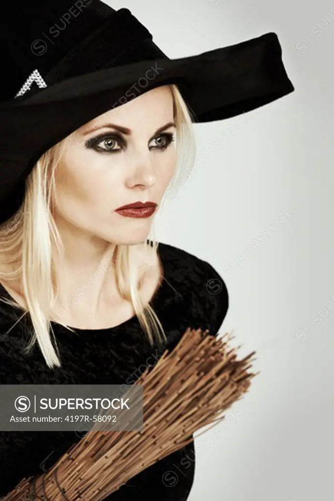 A beautiful blonde witch holding her broomstick up on a white background
