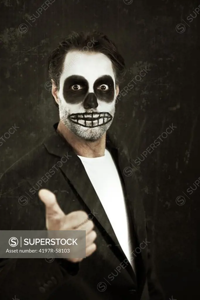 Portrait of a man with skull face paint showing a thumbs up on a white background
