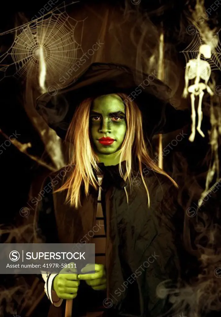 Portrait of a young witch with green skin holding a broomstick