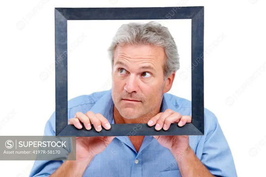 A mature man looking out of the black picture frame he is confined to - Isolated