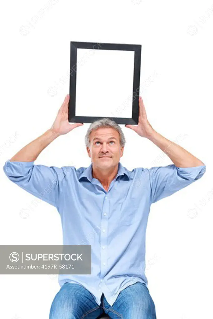 A goodlooking mature man balancing an empty picture frame on his head - Copyspace