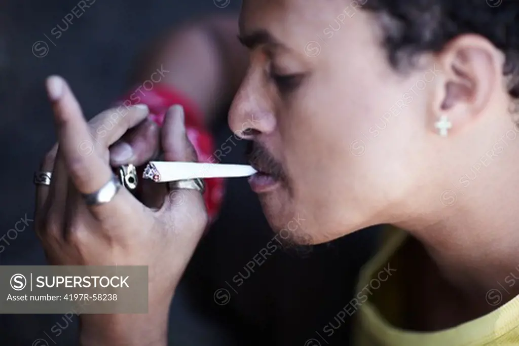 Profile of a young man lighting a joint