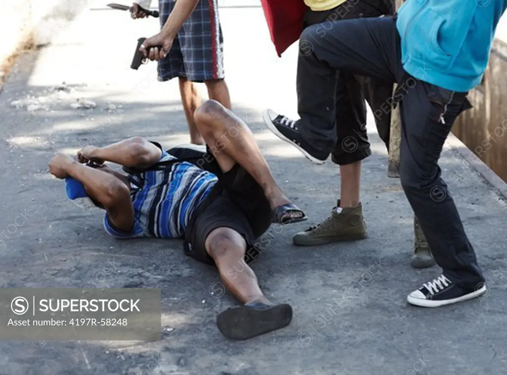 Cropped image of a man being beaten on the ground by a gang